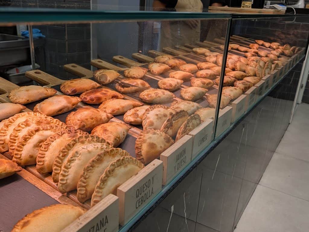 Display case of Argentine empanadas at Sabores Express in Alcalá de Henares, showing the full range of flavors available.