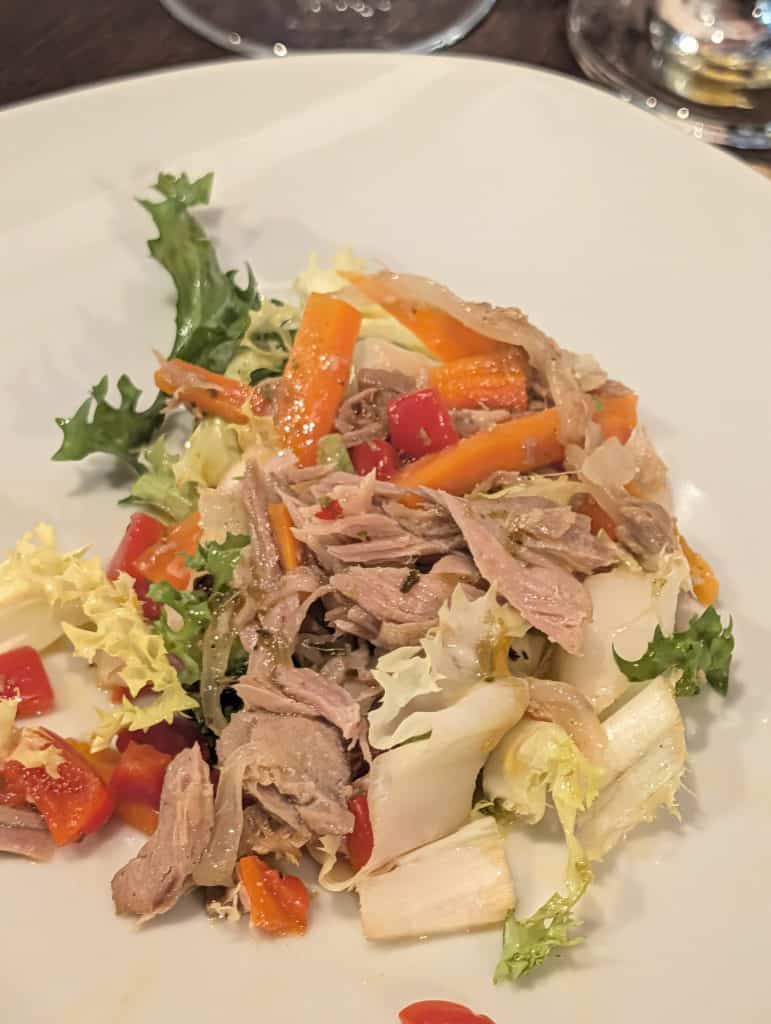 Picture of a plate of ventresca of tuna, served on a bed of escabeche and set alongside roasted piquillo peppers.
