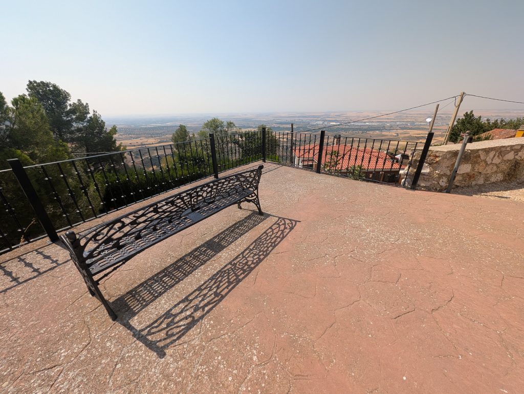 Picture of the mirador of the Iglesia de San Pedro Apóstol in Los Santos de la Humosa. Shows the bench and railing looking out over the valley. 