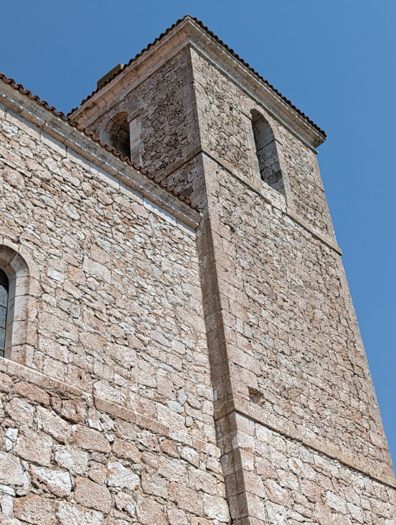 Close-up of the Iglesia de San Pedro Apóstol's bell tower showing the stone banding that marks its three levels. 